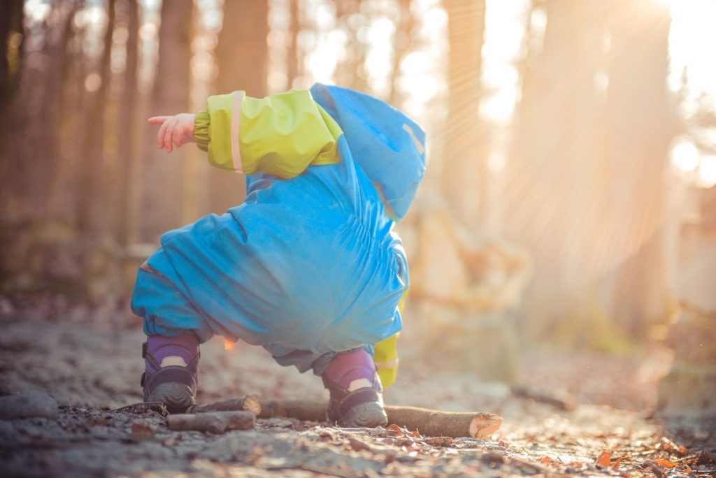 Etapas do desenvolvimento infantil: entenda as 4 fases da infância Na etapa da primeira infância, a criança da imagem está descobrindo o ambiente brincando com a terra e com as folhas.