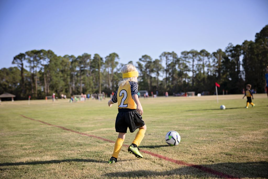 Criança jogando futebol como exemplo de cursos para crianças