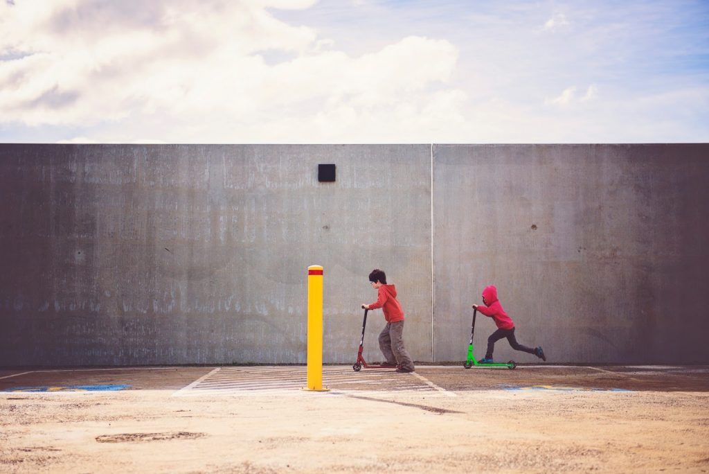 Crianças andando juntas de patinete como exemplo de dinâmica infantil