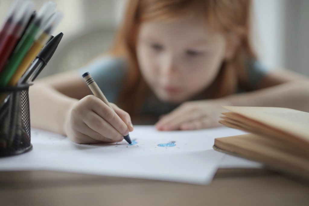 Criança estudando sozinha em casa