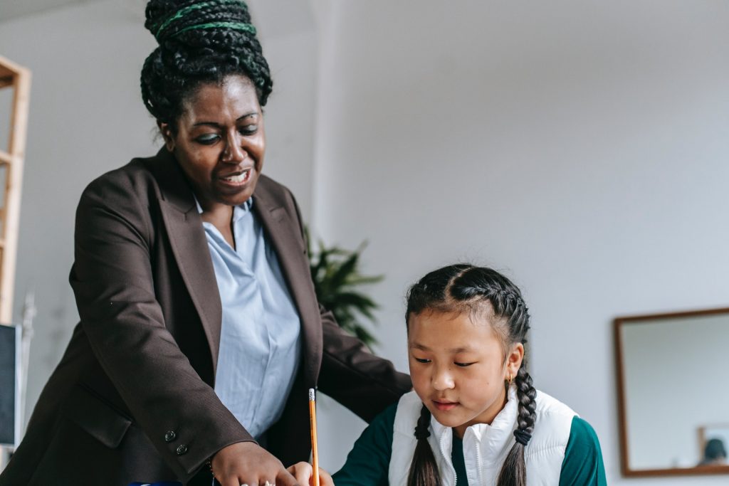 7 benefícios do acompanhamento pedagógico Na imagem, uma pedagoga realiza o acompanhamento pedagógico junto de uma de suas alunas.