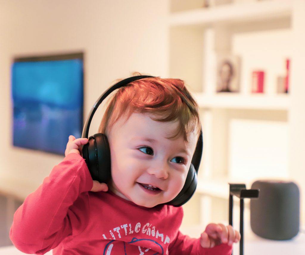 Criança ouvindo música em fones de ouvido, tentando aprender inglês com música.