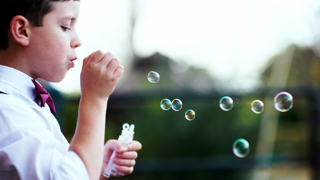 Uma criança brinca com bolhas de sabão na imagem, para o desenvolvimento infantil é importante desenvolver brincadeiras para o desenvolvimento psicoemocional.