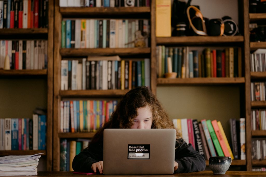 Hábitos para aumentar a motivação para estudar Na imagem, vemos uma estudante com motivação para estudar em seu computador.