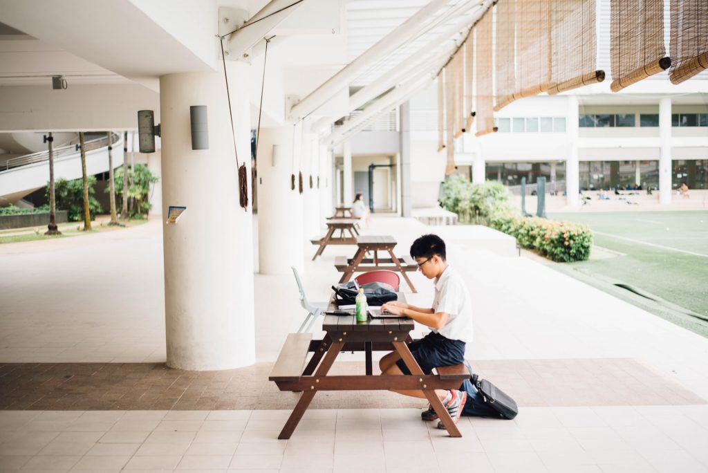 Um aluno está aplicando algumas estratégias de como focar nos estudos no pátio de sua escola.
