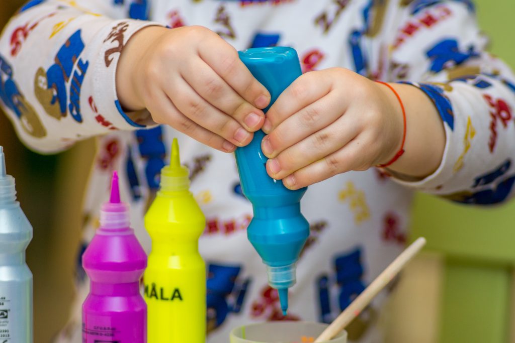 Criança colocando cultura maker em prática, brincando com tintas coloridas.