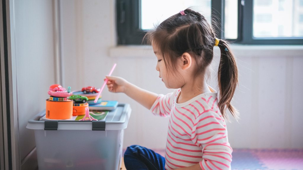 Menina criança brincando de pintar, representando as fases da criança.