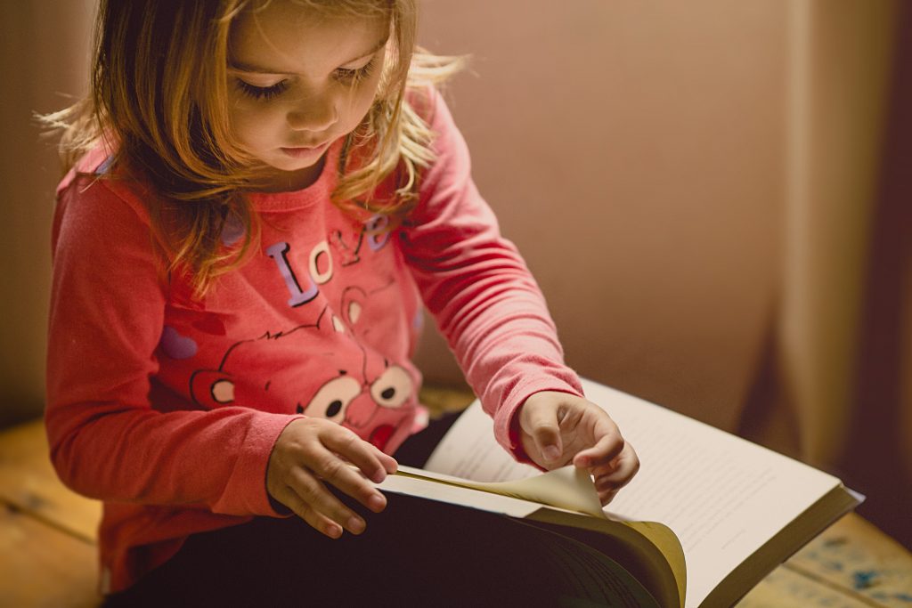 Menina exemplificando o desenvolvimento da criança ao ler um livro.