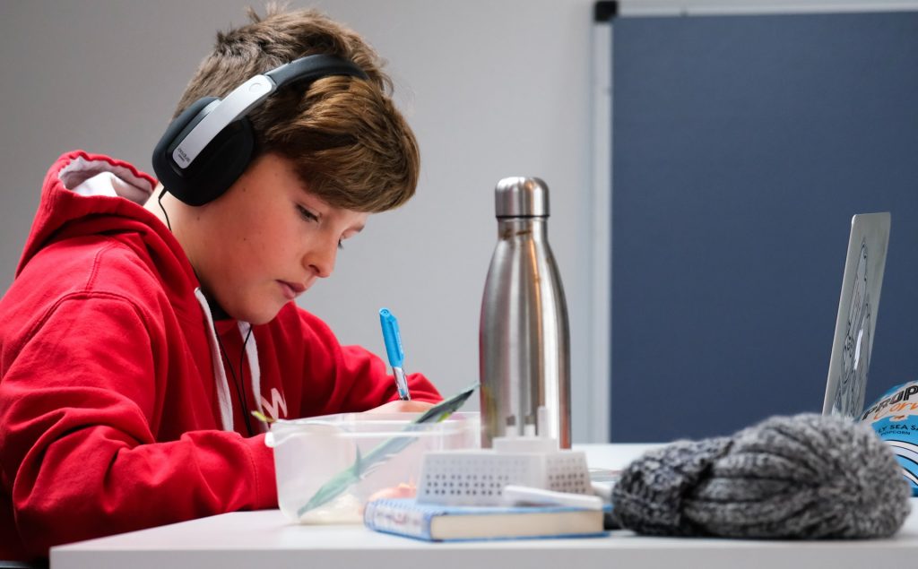 5 dicas para estudar com músicas em inglês Assim como o aluno da imagem faz, ouvir músicas em inglês ajuda no aprendizado passivo.