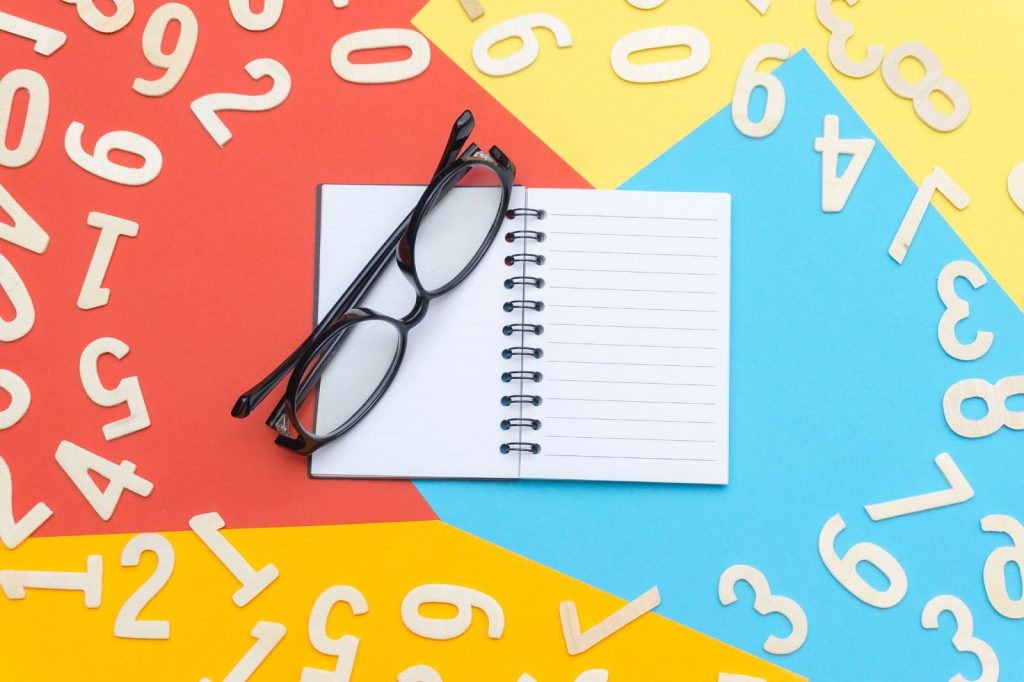 Como são formados os números em inglês caderno em branco e um óculos em cima rodeados de números brancos