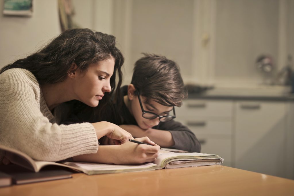 Uma mulher ajudando uma criança com dificuldade de aprendizagem a estudar.