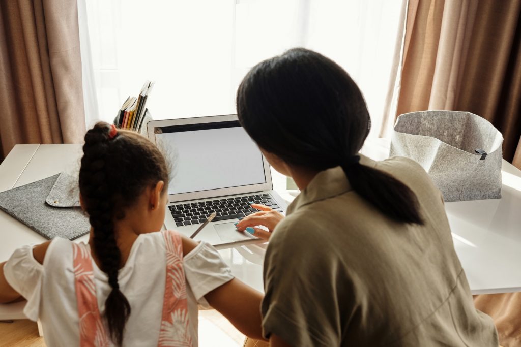 Como ajudar meu filho a se motivar a estudar? Na imagem, uma mãe participa ativamente da rotina de estudos da filha para ajudá-la com a motivação para estudar diariamente.