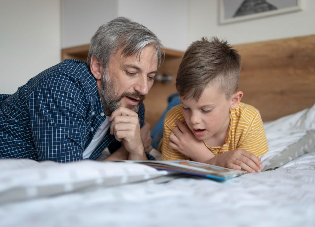 5 dicas de poemas infantis para ler com seus filhos Um pai está lendo um poema infantil para seu filho.