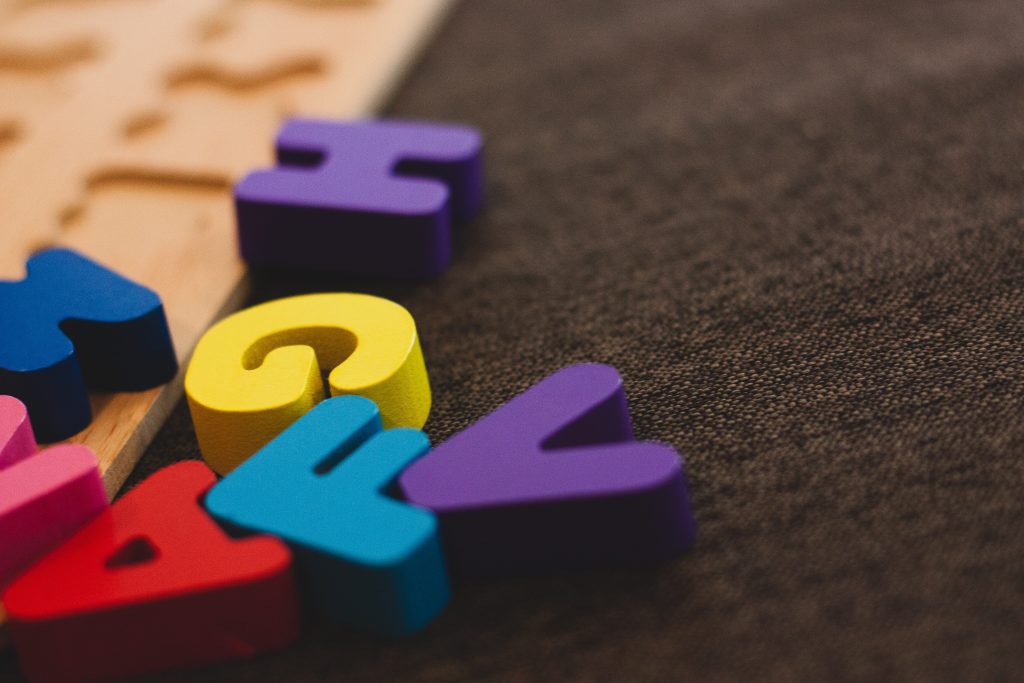 Blocos de letras coloridos espalhados pelo chão, representando vocabulário em inglês.