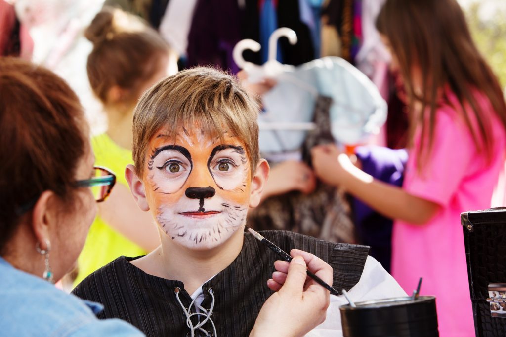 Criança praticando dramatização infantil com o rosto pintado como um leão.