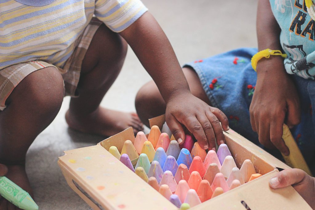 Crianças brincando com giz de cera de cores diversas, exemplificando o que é a metodologia ativa
