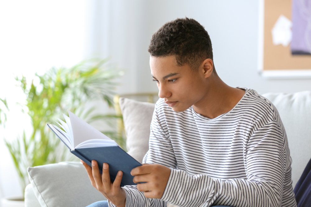 Jovem garoto lendo um livro, um dos 3 fundamentos da língua inglesa para melhor a fluência.