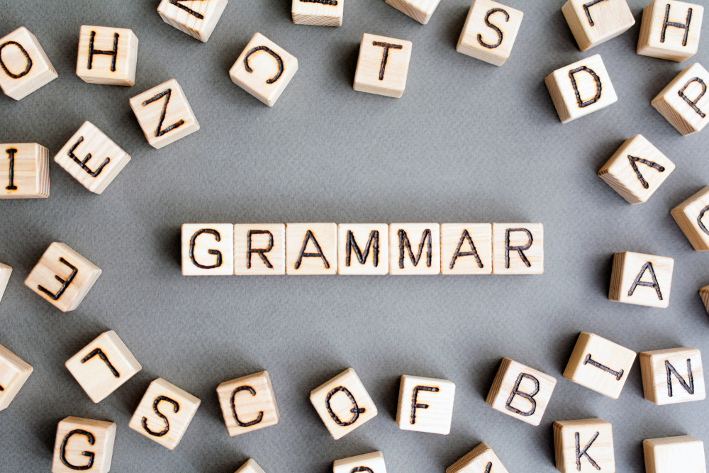 Blocos de madeira formando a palavra grammar, ilustrando o tema gramática inglesa.