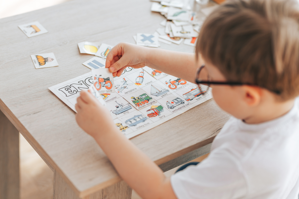 Aprender inglês na infância: imagem de criança brincando com cartões relacionados a objetos e seus nomes em inglês