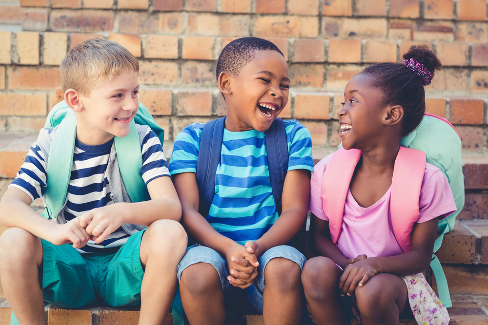 Na imagem, crianças conversando e sorrindo, ilustrando como a conversação em inglês pode ser uma ótima forma de praticar a língua.